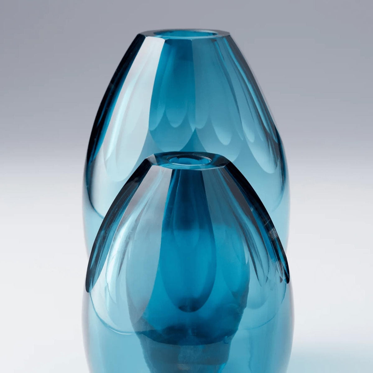 Two elegant ocean blue glass vases, one large and one smaller, with a refined, modern design.