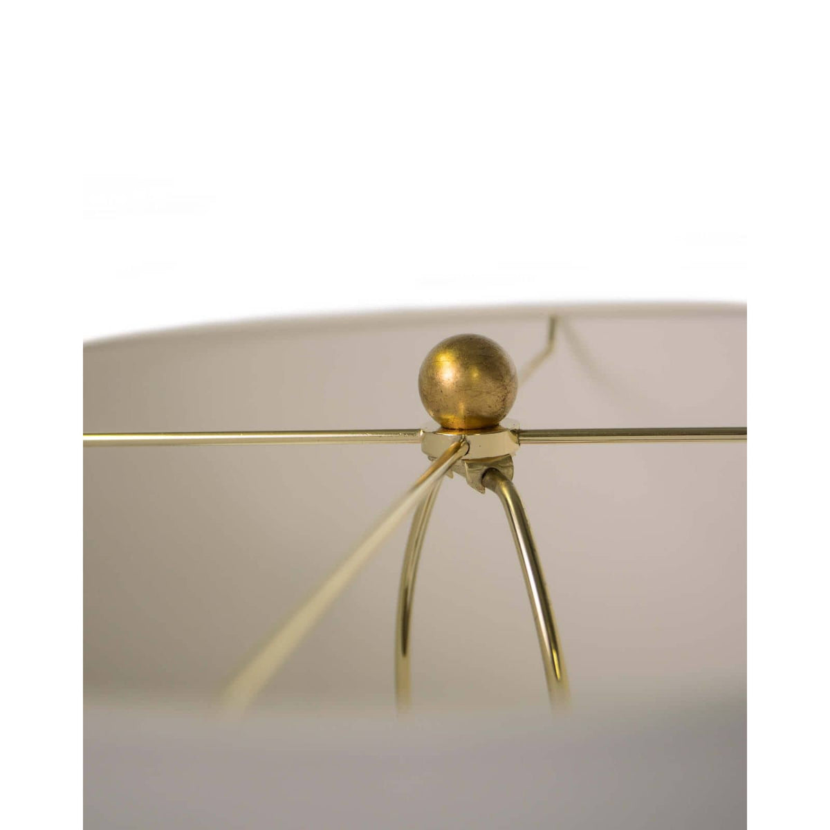 Close-up of Lillian floor lamp's polished brass spider and finial, supporting a natural linen shade.