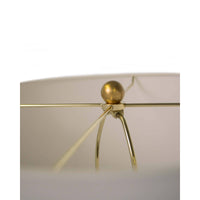 Close-up of Lillian floor lamp's polished brass spider and finial, supporting a natural linen shade.