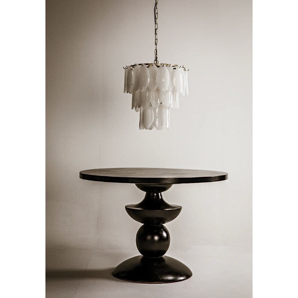 Lotus Petal Chandelier with three tiers of handcrafted white glass petals and an antique brass frame, above a dark round table.