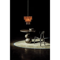 Black/brass Lotus Petal Chandelier with three tiers of milk glass petals over a dark table and chair.