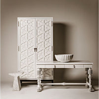 White mahogany hutch with hand-carved geometric doors, next to a matching console table and marble stool.