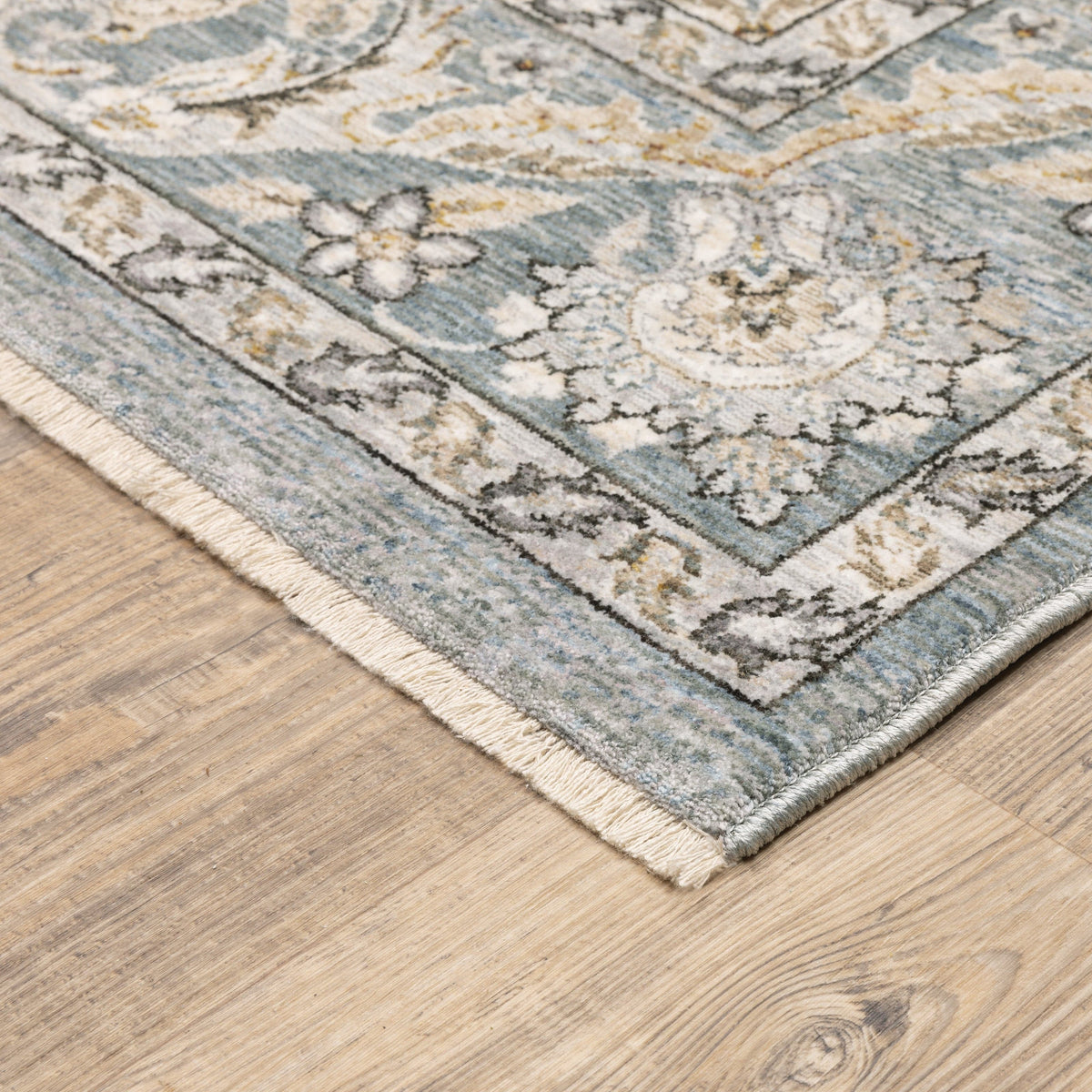 Maharaja Blue & Ivory Traditional Rug with intricate floral patterns and fringe on a wood floor.