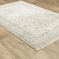 Hand-loomed Malabar Beige & Charcoal Traditional Rug with Persian designs and fringe on wood floor.