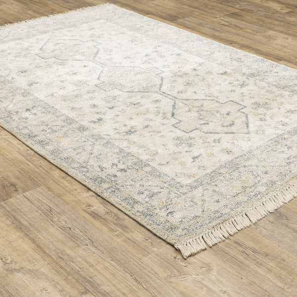 Hand-loomed Malabar Beige & Charcoal Traditional Rug with Persian designs and fringe on wood floor.