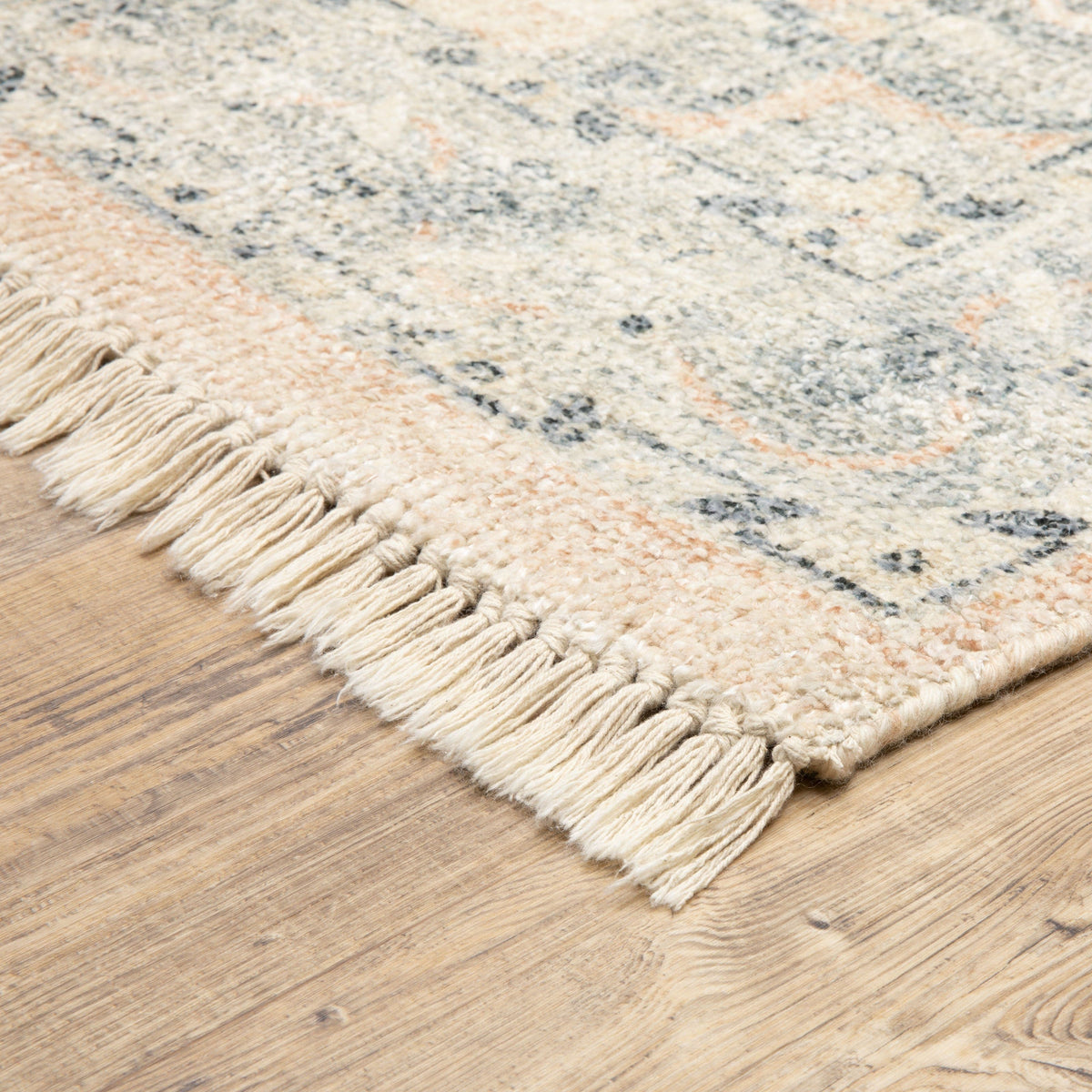 Malabar Beige & Grey hand-loomed rug with subtle Persian designs and fringe on a wood floor.