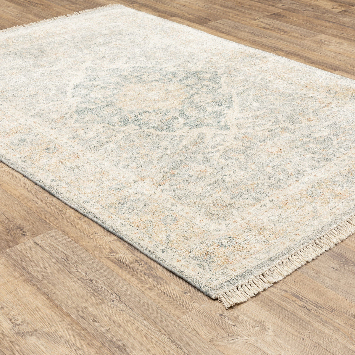 Hand-loomed Malabar Beige & Grey Chenille Traditional Rug with Persian design and fringe on wood floor.