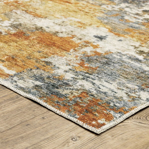 Malibu Blue & Gold washable polyester rug with abstract distressed design and blanket stitch edge on wood floor.