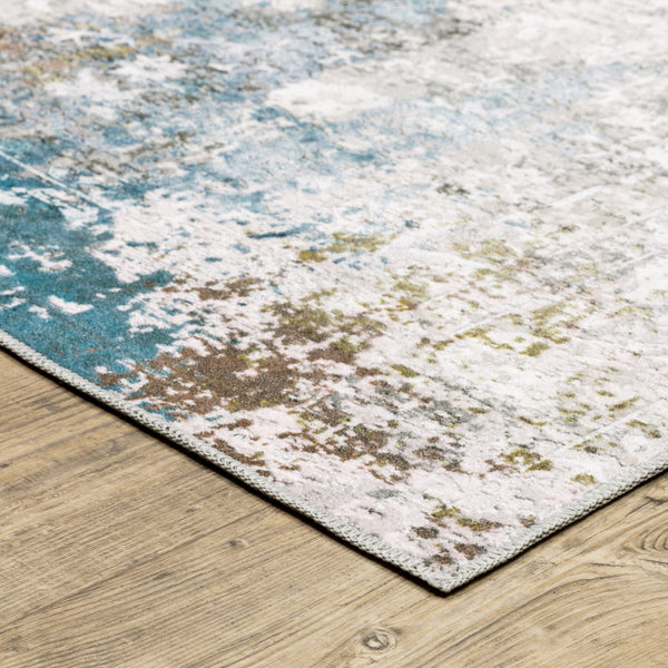 Malibu Ivory & Blue Washable Rug with abstract distressed design and blanket stitch finish on wood floor.