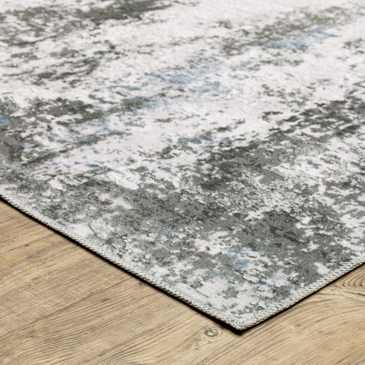 Malibu Ivory & Grey washable polyester rug with abstract distressed design on a wood floor.