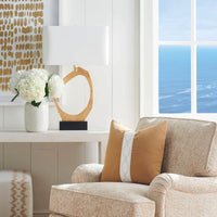 Manhattan Table Lamp with a flowing gold leaf base and rectangular white linen shade, beside a textured armchair.