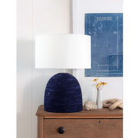 Manuka Table Lamp with a hand-wrapped indigo rope base, white linen shade, and polished nickel accents on a wooden dresser.