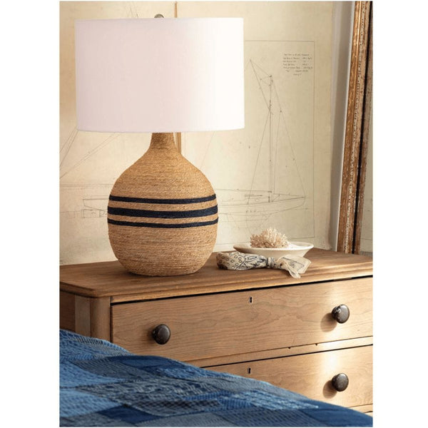 Maren Table Lamp with natural rope-wrapped base, three navy stripes, and a white linen shade on a wooden dresser.