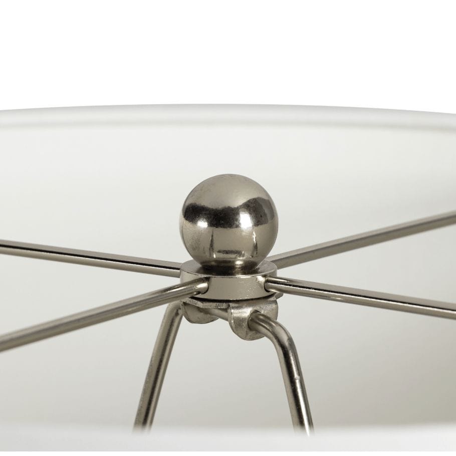 Close-up of a polished nickel spider and finial on a white linen lamp shade.