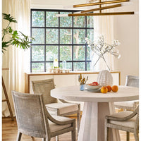 White marble plate on a round dining table, surrounded by chairs, with a large window in the background.