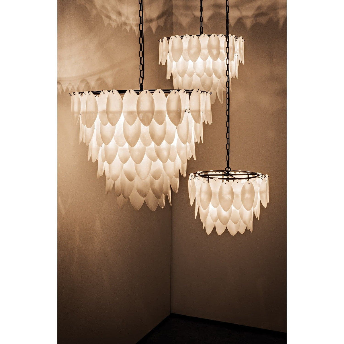 Matte black lotus petal chandelier with three tiers of milk glass petals and antique brass finish.