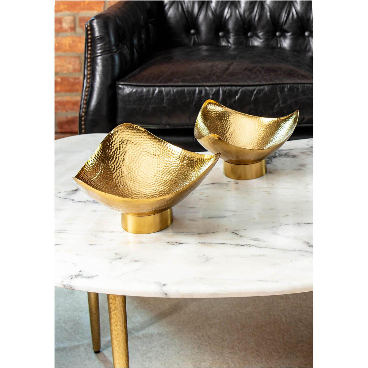 Two Milo large and small brass decorative bowls with hand-hammered texture on a marble coffee table.
