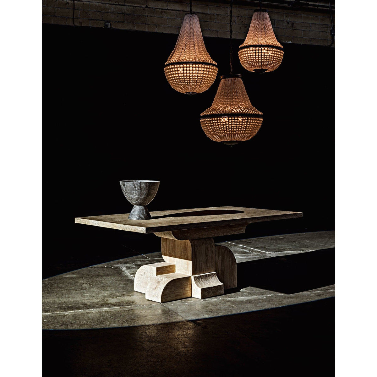 Three black steel Mist chandeliers with beaded glass shades illuminate a modern wood table.