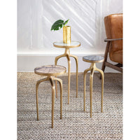 Set of three gold metal mixer tables with round marble tops, varying heights, on a woven rug.