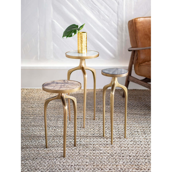 Set of three gold metal mixer tables with round marble tops, varying heights, on a woven rug.