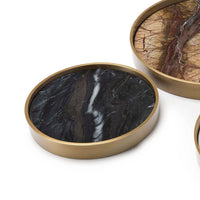 Set of three round marble trays with natural brass frames, featuring unique black and brown veining.