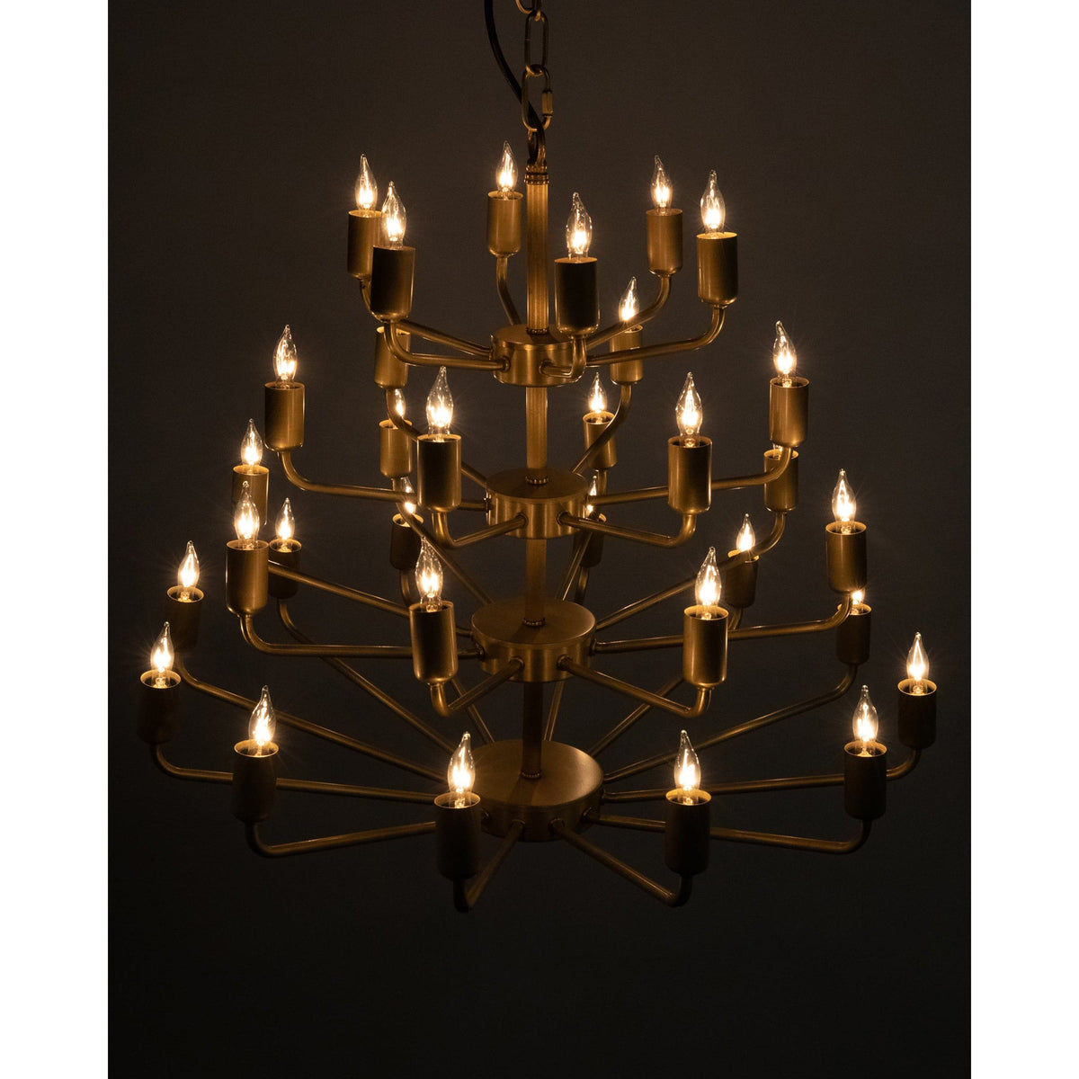 Montoro antique brass chandelier with four tiers of lit bulbs, a modern classic design.