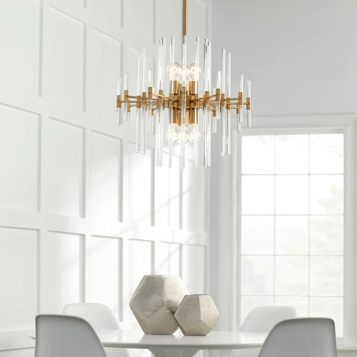 Montreal small aged brass chandelier with linear glass rods, hanging above a white dining table.