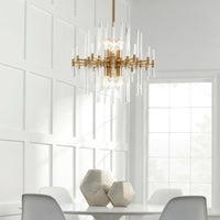 Montreal small aged brass chandelier with linear glass rods, hanging above a white dining table.