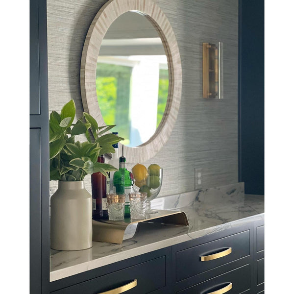 Round multitone bone tile mirror with slender striping, reflecting a coastal look.