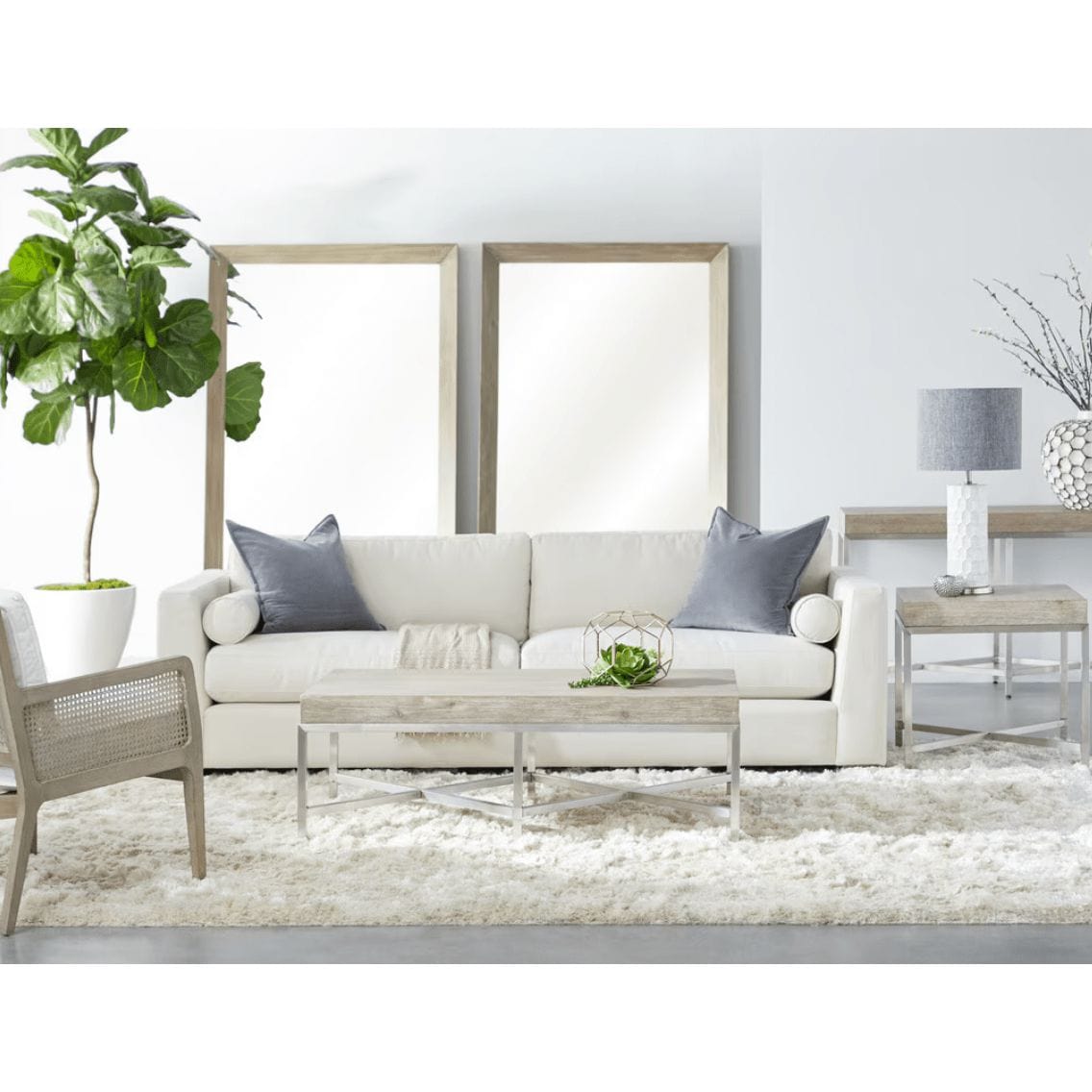 Two large natural gray acacia framed bevelled floor mirrors behind a white sofa in a living room.