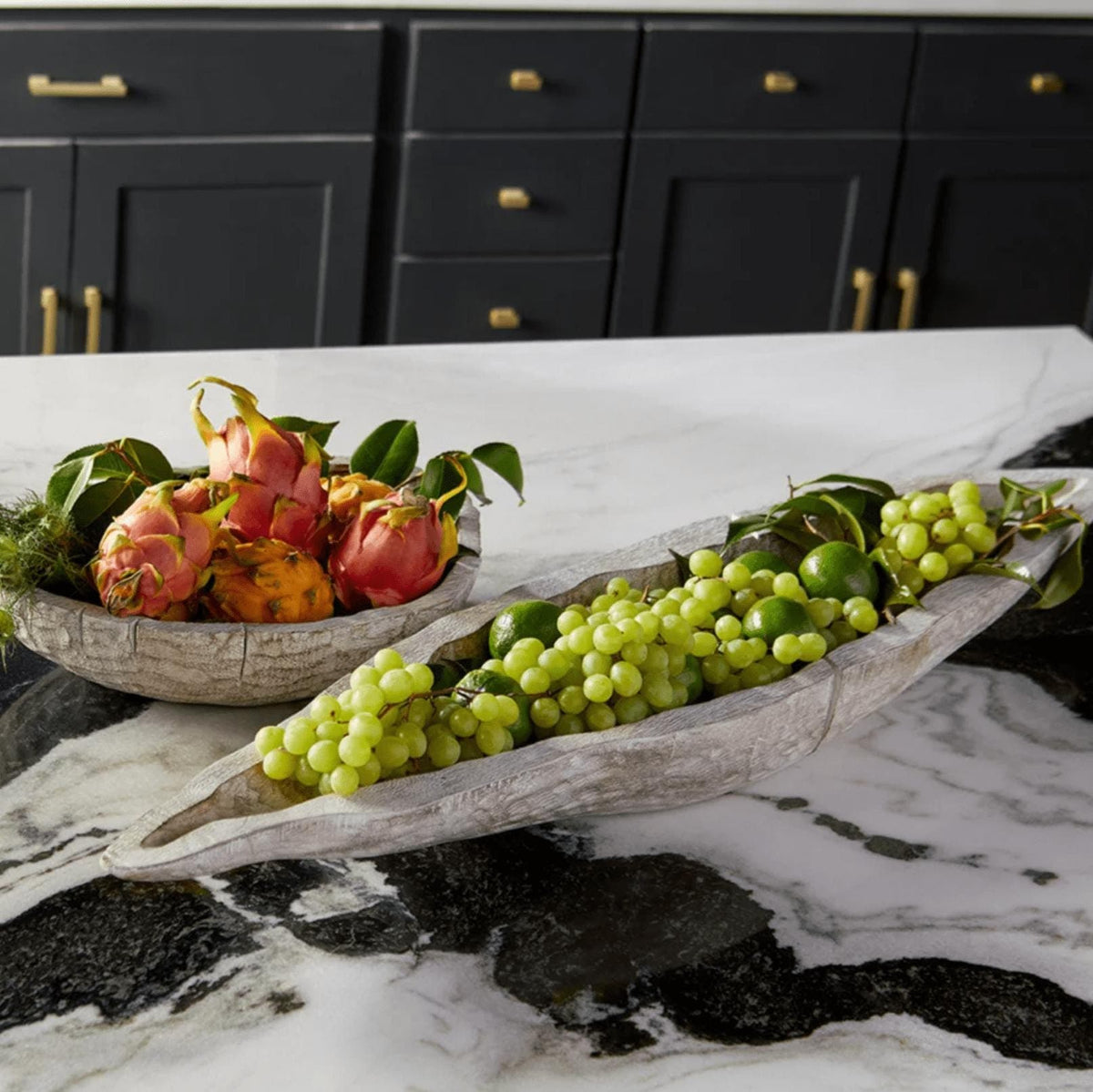 Long whitewashed Ardu wood decorative tray filled with green grapes on a marble counter.