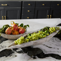 Long whitewashed Ardu wood decorative tray filled with green grapes on a marble counter.