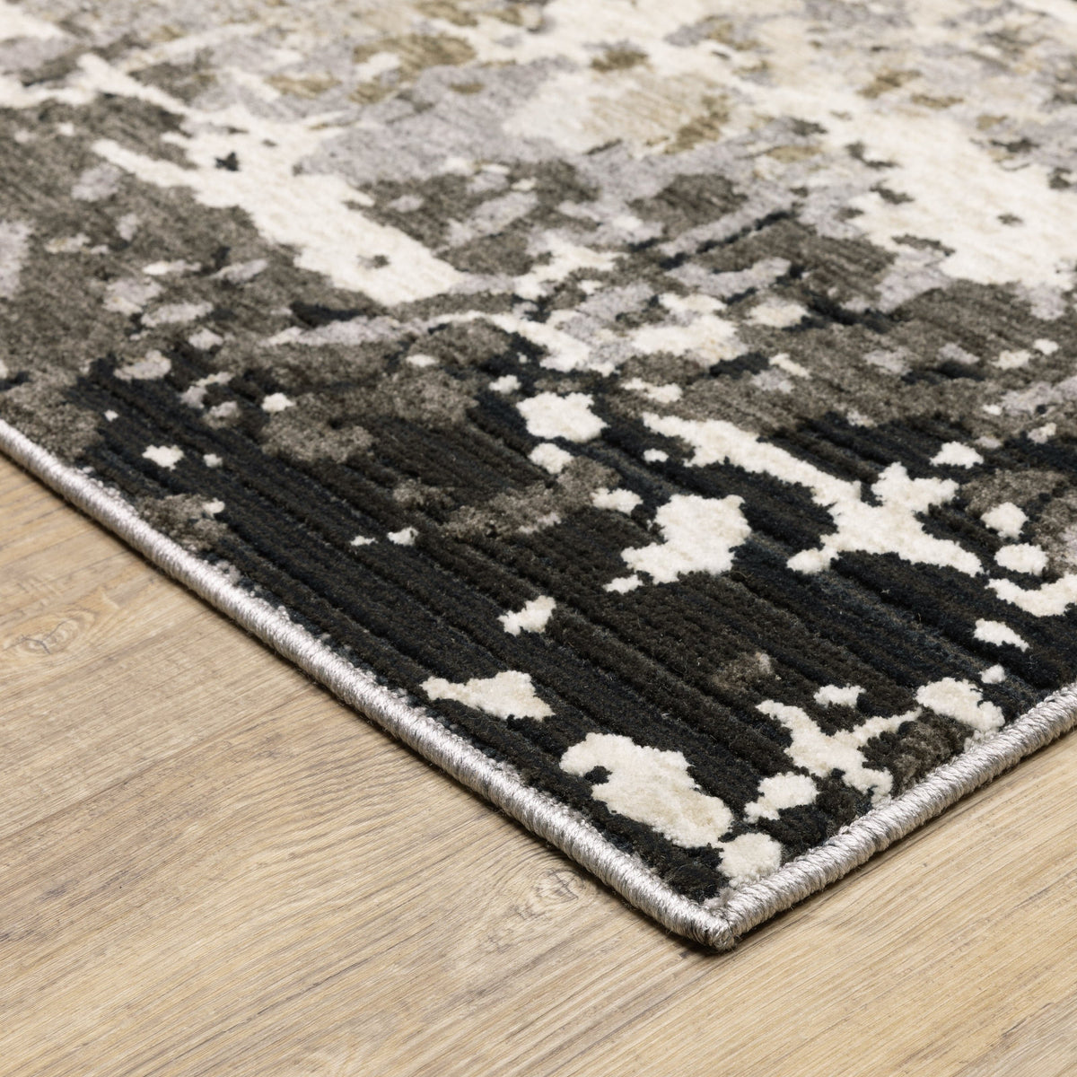 Contemporary polyester rug with abstract beige, ivory, black, and gray patterns on a wood floor.