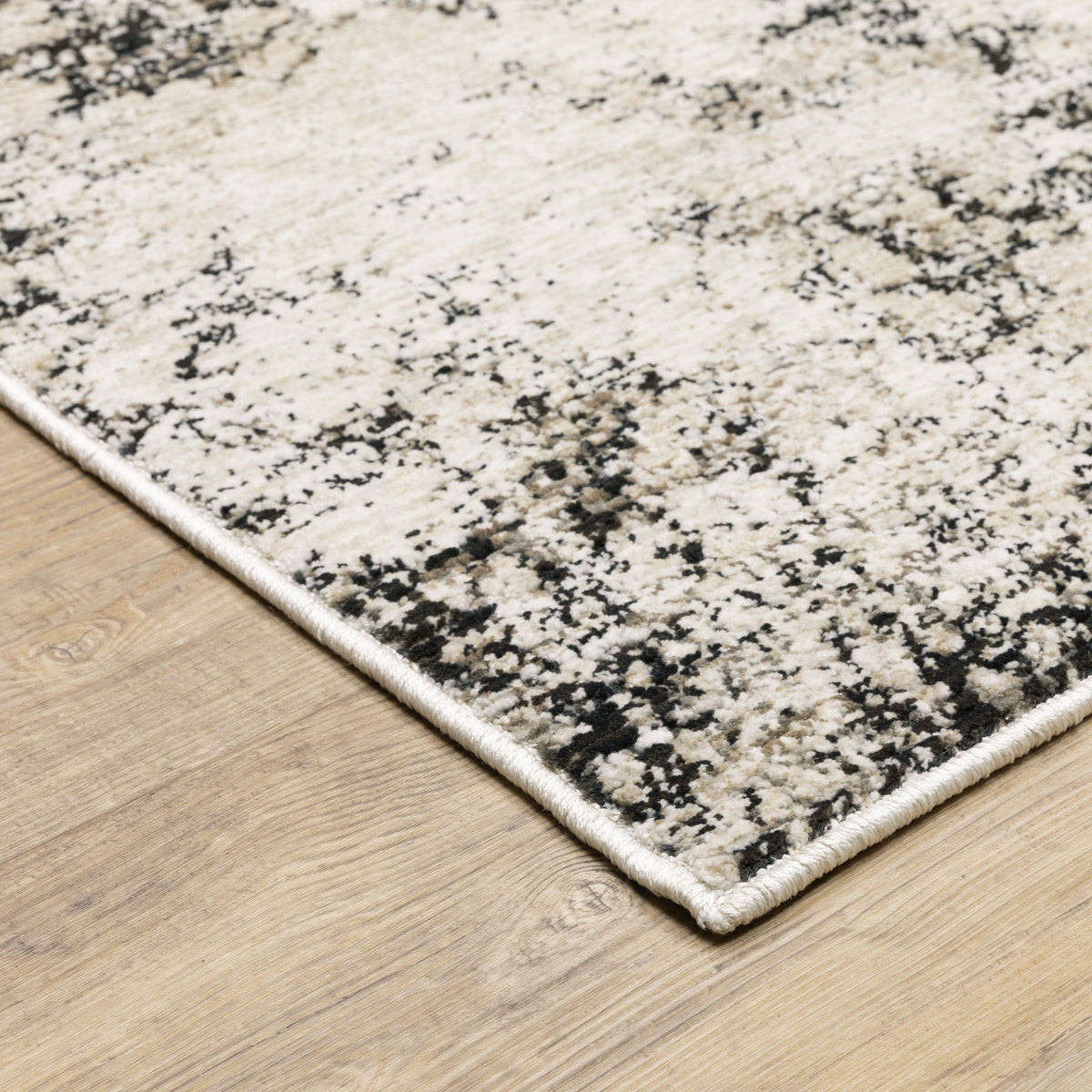 Ivory & grey abstract polyester rug with low-profile texture on a wood floor.