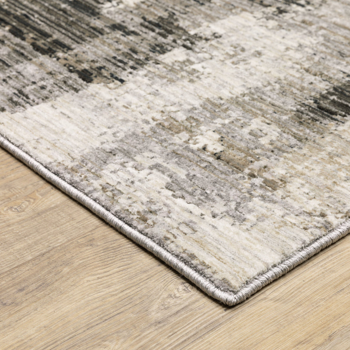 Contemporary ivory, grey, and black abstract polyester rug with a low-profile design on a wood floor.