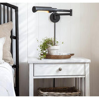 Noble Swing Arm Task Sconce in oil rubbed bronze, with multiple pivoting joints, above a white nightstand.