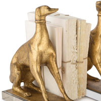 Antiqued gold leaf dog bookends on crystal pedestals, holding books.