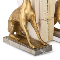 Antiqued gold leaf dog bookends on clear crystal pedestals, holding books.