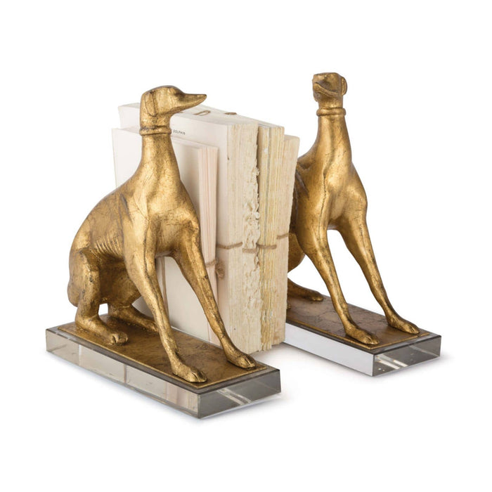 Antiqued gold leaf dog bookends on crystal pedestals, holding books.