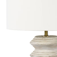 Nova Wood Table Lamp with white-washed carved wood body, natural linen drum shade, and brass finial.