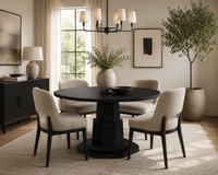 Dining room with a round black table and beige chairs, featuring a chandelier and large windows.