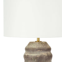 Ola ceramic table lamp with an organic, wavy earthenware base in earthen brown and tan, topped with a white linen drum shade.