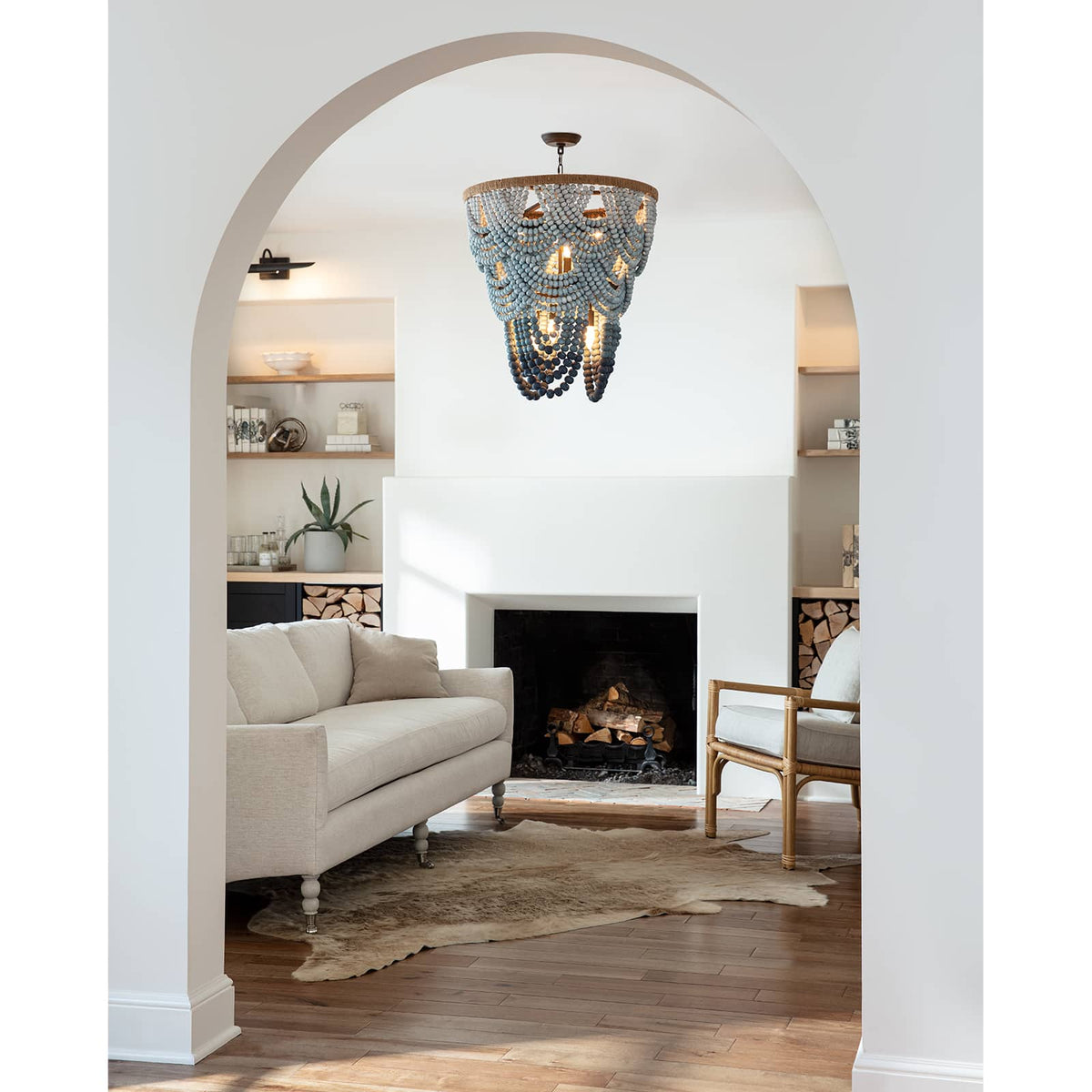 Ombre wood bead chandelier with blue gradient beads, jute frame, and 6 candelabra lights in a living room.