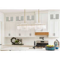 Orinder 8-light aged brass linear chandelier with textured glass panels in a white kitchen.