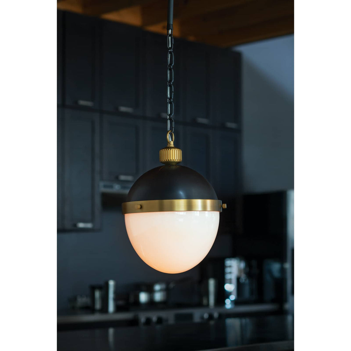 Otis Medium Pendant with blackened natural brass and translucent white milk glass, suspended by a chain.
