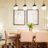 Otis Small Blackened Natural Brass Pendant with white milk glass globe, hanging above a dining table.