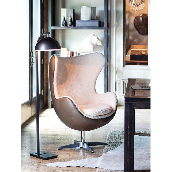 Black Otto floor lamp with swiveling shade and arching neck, beside a modern armchair.