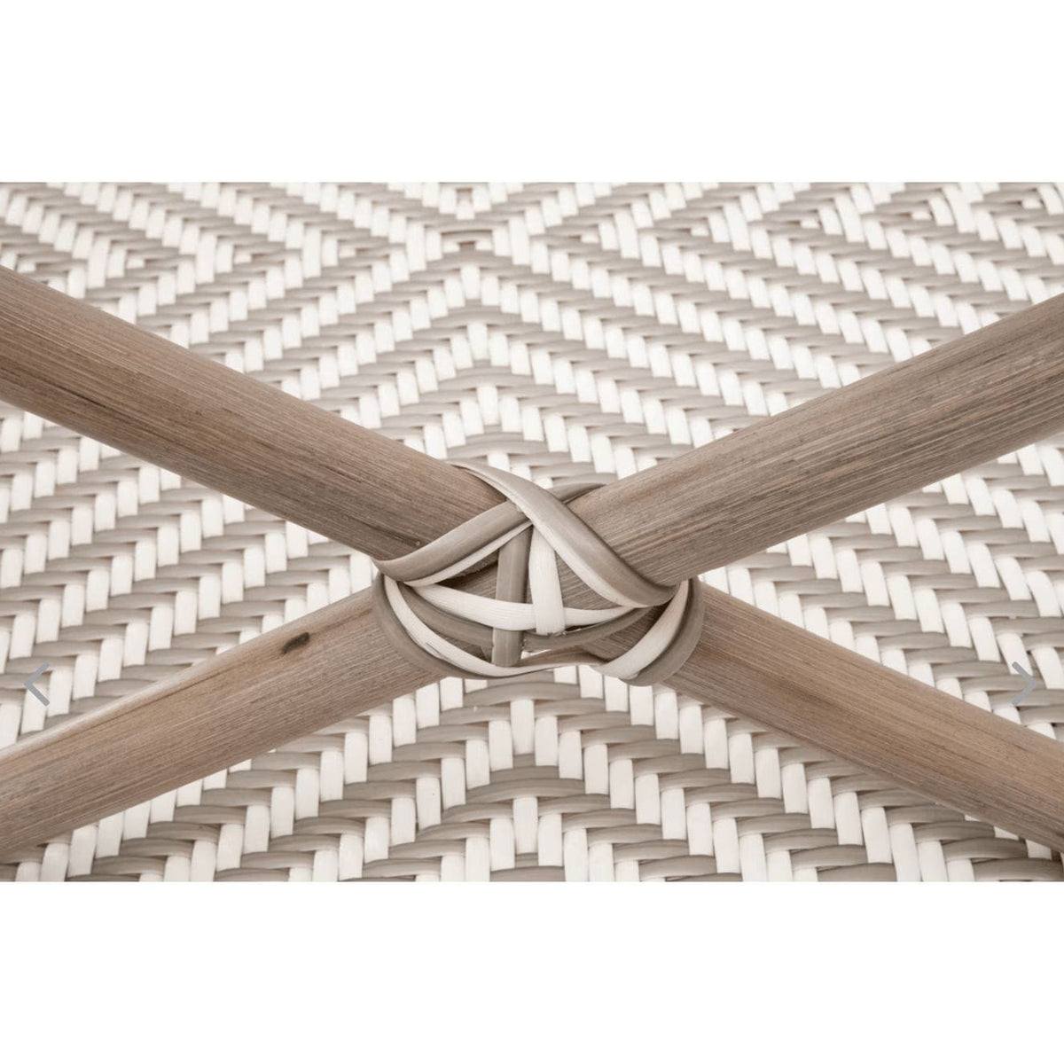 Close-up of a Palisades Stone & White Rattan Bench, showing the handwoven white and gray rattan pattern with crossed natural wood-toned legs.