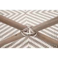 Close-up of a Palisades Stone & White Rattan Bench, showing the handwoven white and gray rattan pattern with crossed natural wood-toned legs.