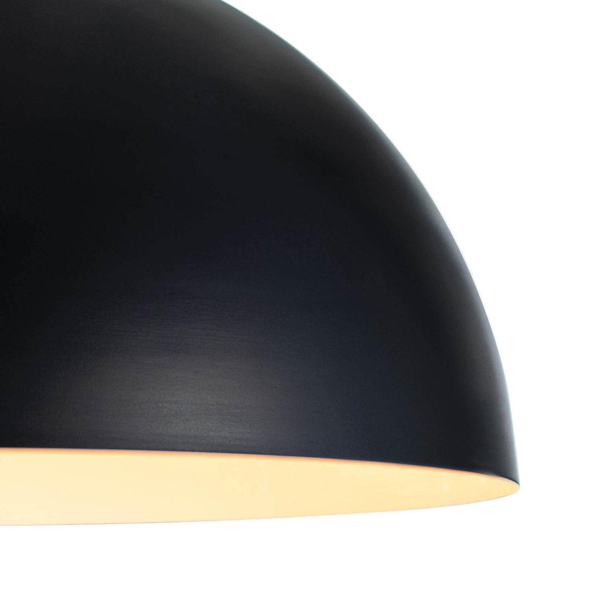 Close-up of a sleek, black metal dome pendant light with a warm glow.